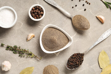 Bowl with black pepper powder and different spices on grey background