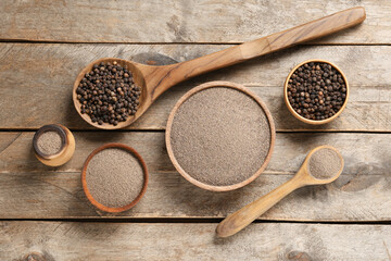 Bowls with black pepper powder and peppercorns on wooden background