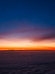 A breathtaking sunrise above the clouds, painting the sky with warm hues of orange, pink, and deep blue