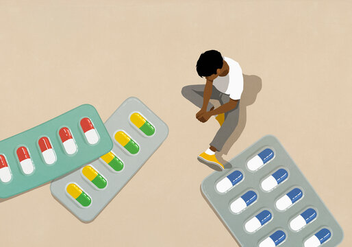 High angle view man looking down at large medication pills in blister packs
