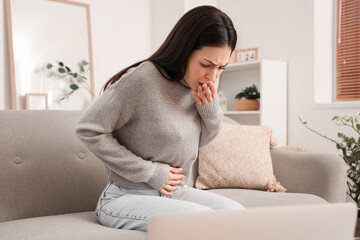 Young woman feeling sick on sofa at home