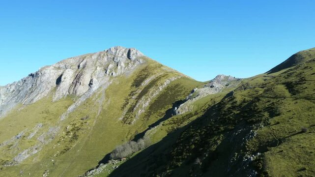 Majestic mount txindoki peak dominating landscape in gipuzkoa province. Rugged limestone cliffs and verdant mountainsides under clear blue sky in basque country