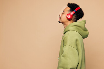 Side view young man of African American ethnicity he wear green hoodie casual clothes listen to...