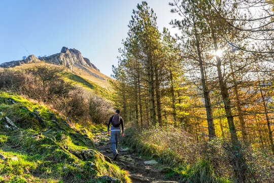 Hiker exploring mount txindoki trail during golden sunset in basque country