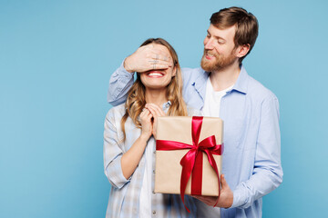 Obraz premium Young couple two friends family man woman wear shirt casual clothes together give present box with gift ribbon bow cover eyes isolated on pastel plain light blue background studio. Lifestyle concept.