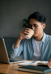 Young Asian professional drinking coffee and working on laptop at home office