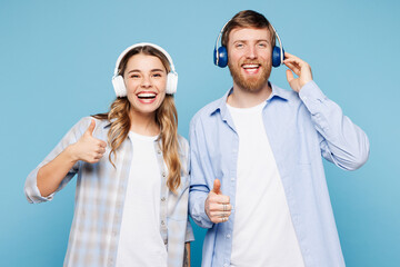 Young fun couple two friends family man woman wear shirt casual clothes together listen to music in headphones isolated on pastel plain light blue cyan background studio portrait. Lifestyle concept.