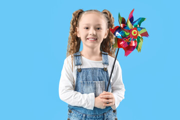 Cute little girl with toy windmill on blue background