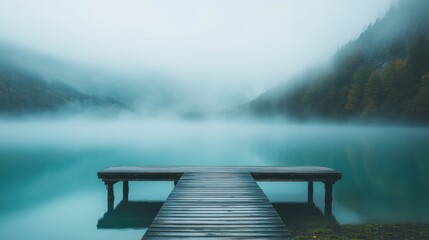 Naklejka premium A peaceful scene of a wooden quay on a turquoise mountain lake, disappearing into the fog.