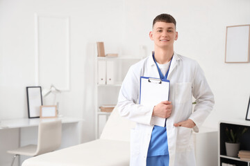 Male medical intern with clipboard in clinic