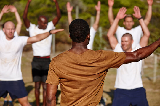 Men, fitness or back with soldiers for military bootcamp, physical activity or training on grass field. Male people, trainer or superior officer with team or army in drill for endurance test or exam