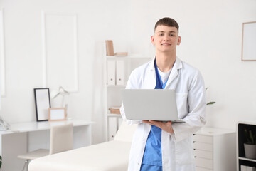 Male medical intern with laptop in clinic