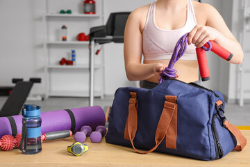 Sporty woman taking skipping rope from bag at gym