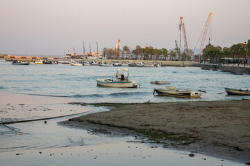 Boats anchored in shallow water as the sun sets over the harbor during early evening in a coastal...