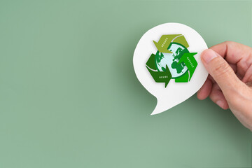 For recycle volunteer, campaign, reduce, reuse, recycle, net zero concept. Hand hold real white speech bubble paper cut with green recycle symbol and earth icon, copy space included