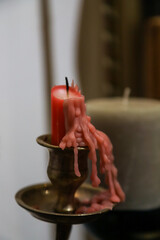Dripping red candle wax on silver candlestick beside a gray candle in a dimly lit room creating a cozy ambiance in the evening