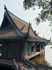 Naklejka premium Traditional temple with intricate carvings sits by the water's edge