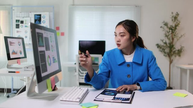 Businesswoman analyzing financial data on computer and documents.