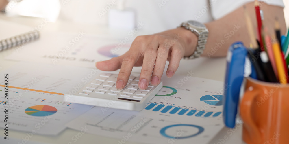Poster close-up of a hand using a calculator to analyze financial data, emphasizing strategy and calculatio