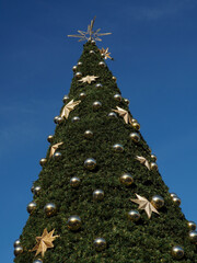 Christmas Tree with Gold and Silver Baubles Against Clear Blue Sky, Festive Holiday Decoration
