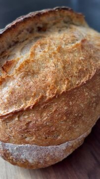 Artisan bread in close-up, showcasing its crunchy crust and warm golden tones. White mica dust adds texture against the dark backdrop, enhancing the fresh, homemade appeal