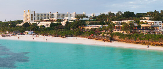 Fototapeta premium Panorama of Zanzibar shore with sandy beach,azure water and luxury resort at sunset. Summer travel in Zanzibar, Africa,Tanzania.