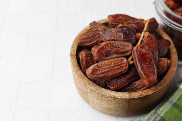 Tasty dried dates on white tiled table, closeup. Space for text