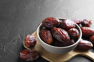 Tasty dried dates in bowl on grey table, closeup. Space for text