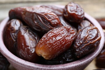 Many tasty dried dates in bowl on table, closeup