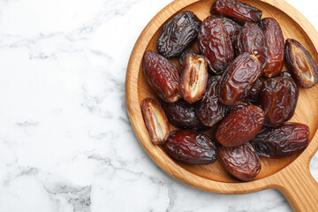 Many tasty dried dates on white marble table, top view. Space for text