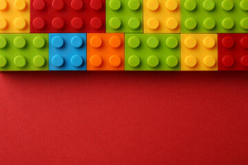 Construction toy. Colorful building bricks on red background, top view with space for text