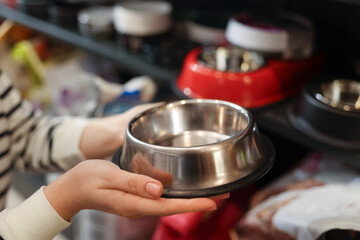 Woman choosing feeding bowl in pet shop, closeup