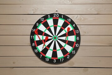 Dart board and arrows on wooden background, top view