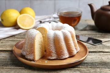 Delicious lemon cake with powdered sugar on wooden table, closeup