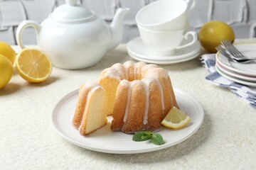 Delicious lemon cake with glaze and mint on light textured table, closeup