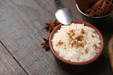 Tasty rice pudding with cinnamon served on wooden table, closeup. Space for text