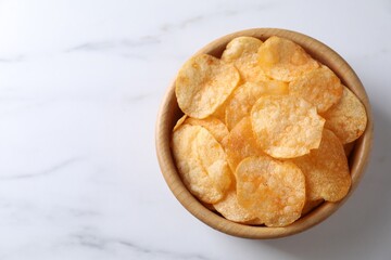 Tasty potato chips in bowl on white marble table, top view. Space for text