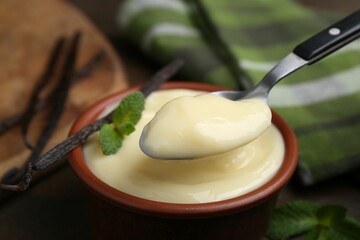 Taking tasty vanilla with spoon on table, closeup