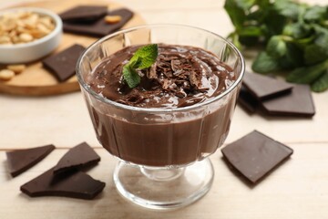 Tasty pudding with mint and pieces of chocolate on white wooden table, closeup