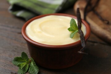 Tasty vanilla pudding, mint and pod on wooden table, closeup