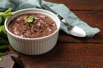 Tasty chocolate pudding in bowl on wooden table, closeup