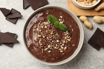 Delicious chocolate mousse in bowl and ingredients on grey table, flat lay