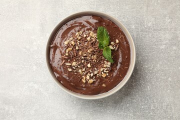 Delicious chocolate mousse in bowl on grey table, top view