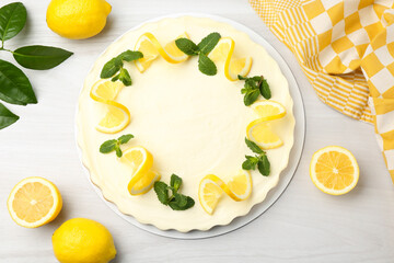Delicious lemon cheesecake with mint and fresh fruits on white wooden table, flat lay