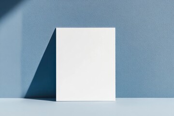 Fototapeta premium A4 white card standing on a blue wall, mockup template, minimalist style, close-up, soft lighting, simple background