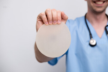 doctor holding breast enlargement implant in hands, plastic surgery concept, beauty enhancement,...