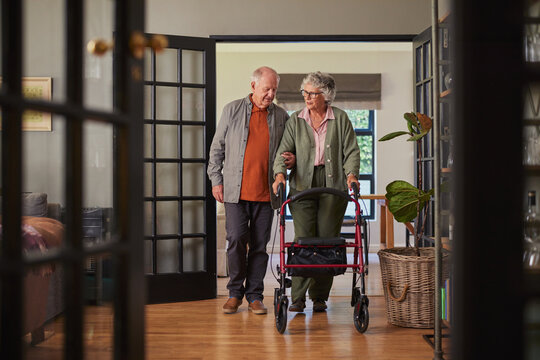 Senior husband helping old wife with medical walker