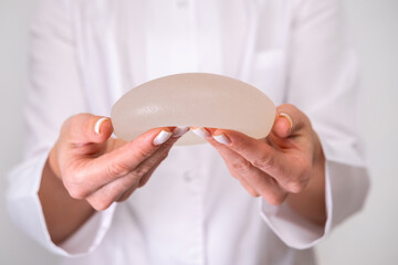 doctor holding breast enlargement implant in hands, plastic surgery concept, beauty enhancement,...