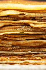 Close-up of a stack of a fried pancakes folded into triangles for Maslenitsa or Shrovetide. Traditional Russian holiday dish for a feast. Macro photography