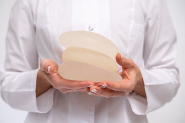 doctor holding breast enlargement implant in hands, plastic surgery concept, beauty enhancement,...